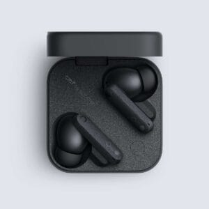 Open charging case containing two black wireless earbuds on a speckled inner tray with the lid raised above the case edge.